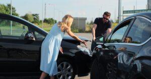 A male and female drivers are stressed as they gesture at their cars and argue over a car accident as they wonder can you claim a car accident without a police report